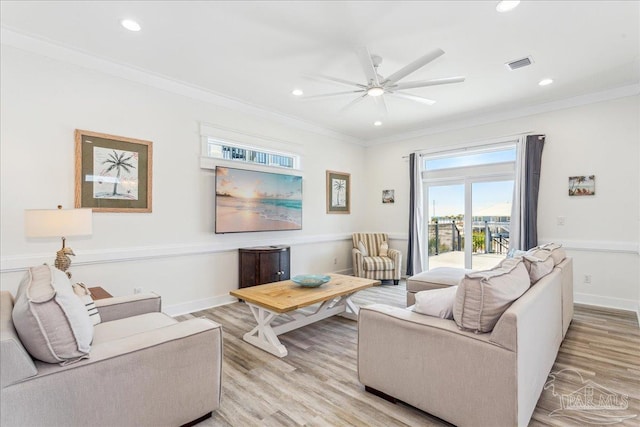 living area featuring ornamental molding, light wood-type flooring, visible vents, and baseboards