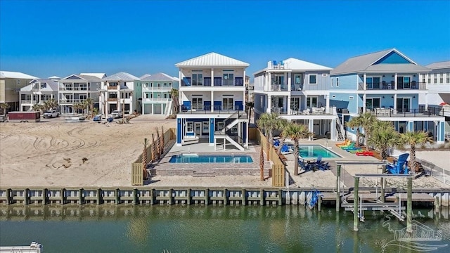 rear view of property featuring a water view, a residential view, an outdoor pool, and an in ground hot tub