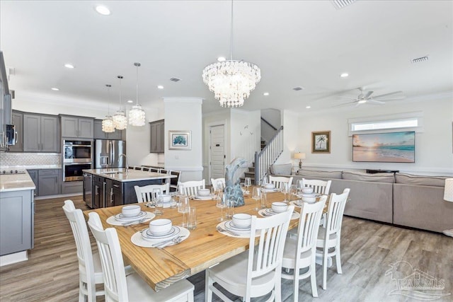 dining space featuring light wood finished floors, stairs, visible vents, and crown molding