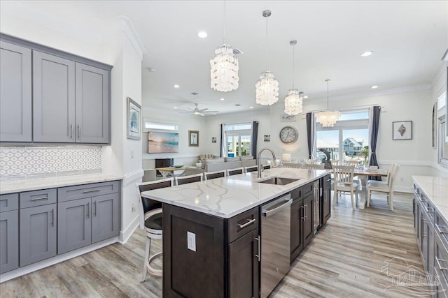 kitchen featuring a breakfast bar, a wealth of natural light, decorative backsplash, a sink, and dishwasher