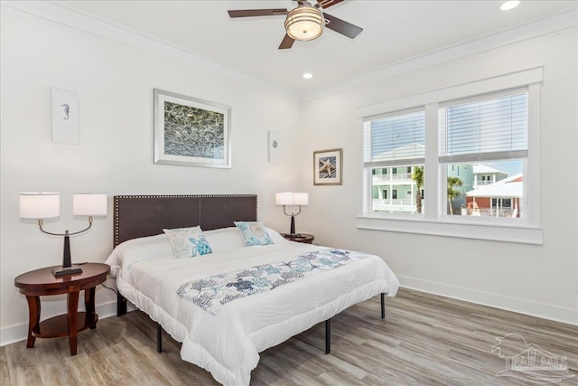 bedroom featuring light wood finished floors, baseboards, crown molding, and recessed lighting