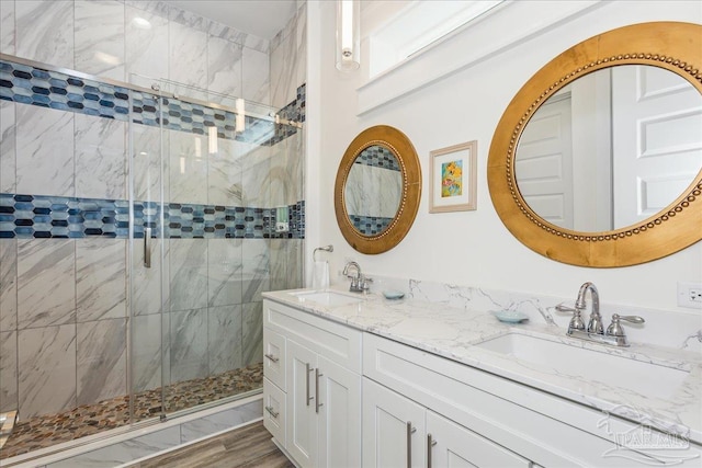 bathroom featuring double vanity, a stall shower, and a sink