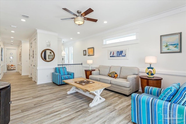 living room with light wood-type flooring, visible vents, crown molding, and recessed lighting