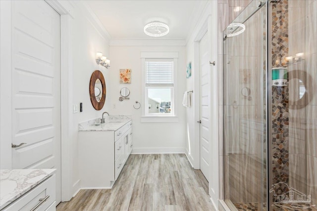 full bathroom with a stall shower, baseboards, wood finished floors, crown molding, and vanity