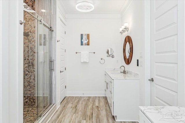 full bathroom with baseboards, wood finished floors, crown molding, vanity, and a shower stall