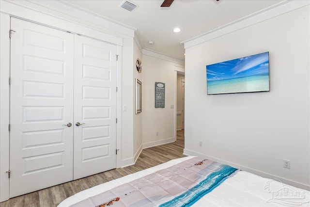 unfurnished bedroom featuring wood finished floors, visible vents, baseboards, a closet, and crown molding