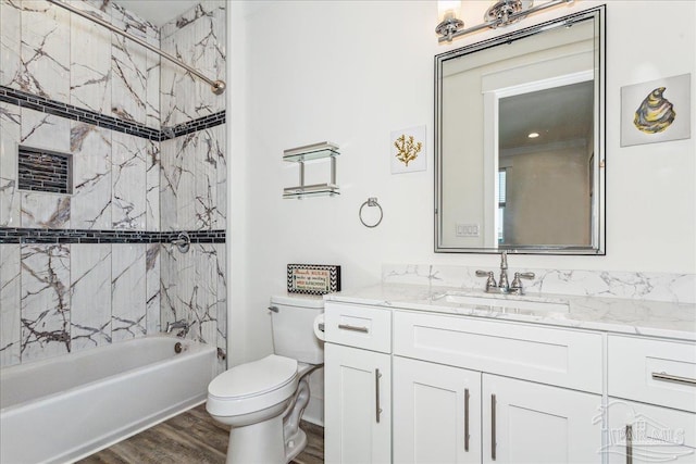 bathroom with toilet, washtub / shower combination, wood finished floors, and vanity