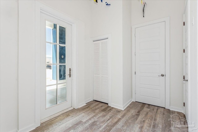 doorway with baseboards and wood finished floors