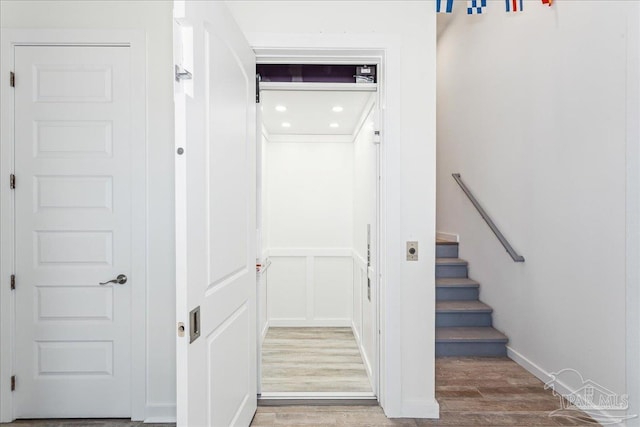 stairway with baseboards, a decorative wall, and wood finished floors