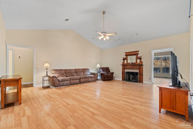 living room featuring ceiling fan, vaulted ceiling, light hardwood / wood-style flooring, and a fireplace