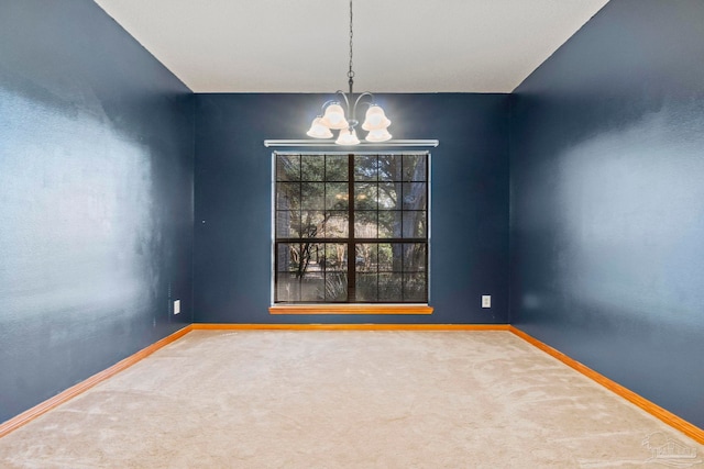 carpeted spare room with an inviting chandelier