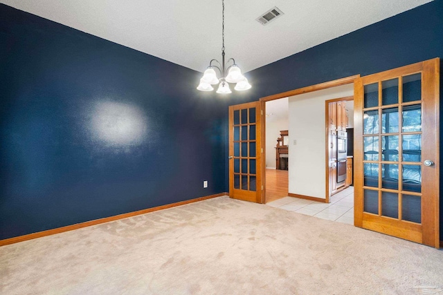 unfurnished room featuring a textured ceiling, a chandelier, light colored carpet, and french doors