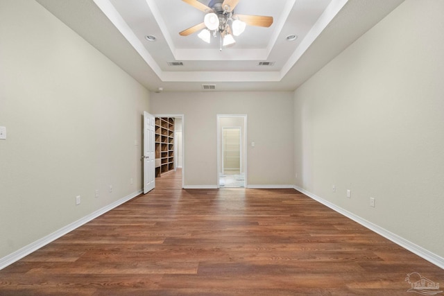 unfurnished room with dark wood-type flooring, a tray ceiling, and ceiling fan