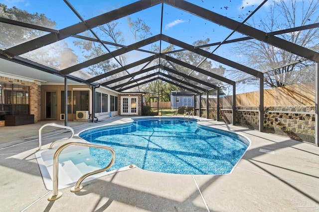 view of swimming pool featuring a patio area, a lanai, and a storage shed