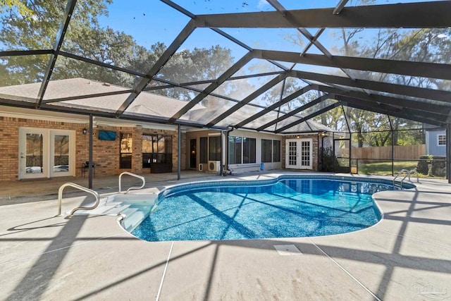 view of pool featuring glass enclosure, french doors, and a patio