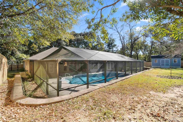 view of pool with glass enclosure, a lawn, a storage unit, and a patio