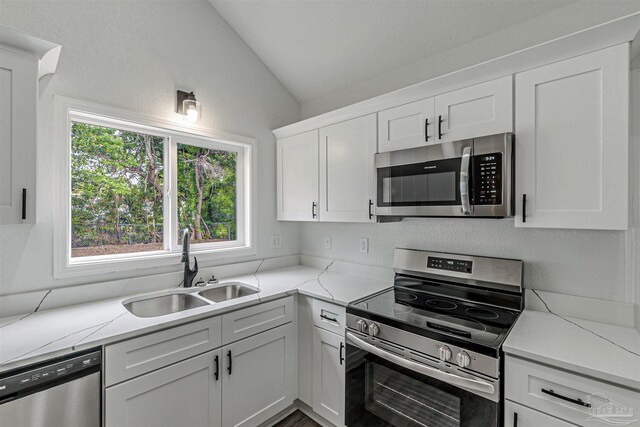 214 Thayer Ave, Pensacola, FL 32507 - kitchen with white cabinetry, appliances with stainless steel finishes, light stone counters, a sink, and lofted ceiling