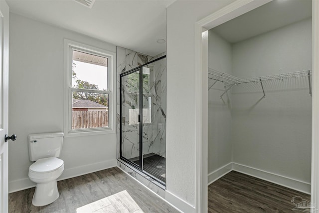 214 Thayer Ave, Pensacola, FL 32507 - bathroom featuring baseboards, toilet, a walk in closet, wood finished floors, and a marble finish shower