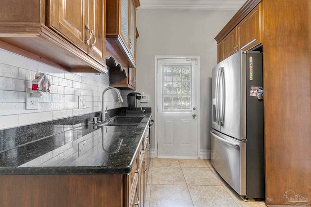 kitchen with dark stone countertops, light tile patterned flooring, backsplash, sink, and stainless steel fridge with ice dispenser