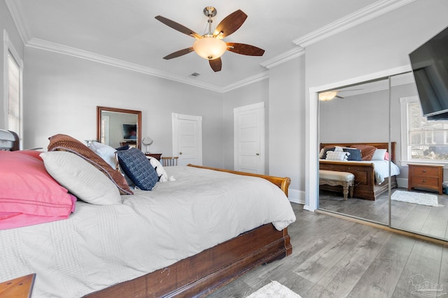 bedroom with a closet, light hardwood / wood-style floors, ceiling fan, and crown molding