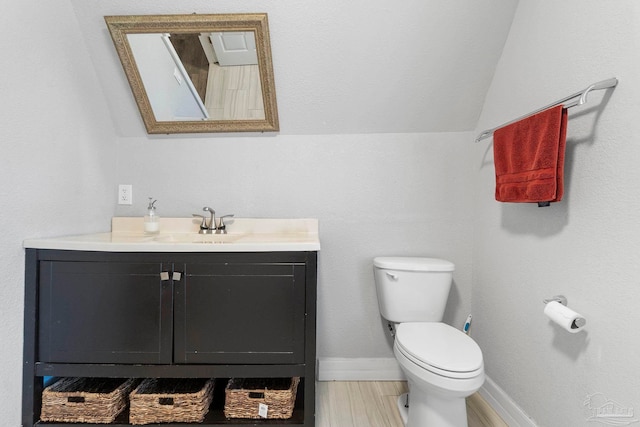 bathroom featuring hardwood / wood-style floors, lofted ceiling, vanity, and toilet