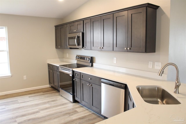 kitchen featuring appliances with stainless steel finishes, lofted ceiling, dark brown cabinetry, and sink