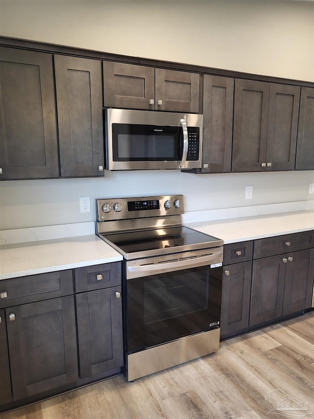 kitchen featuring appliances with stainless steel finishes, dark brown cabinetry, and light hardwood / wood-style floors