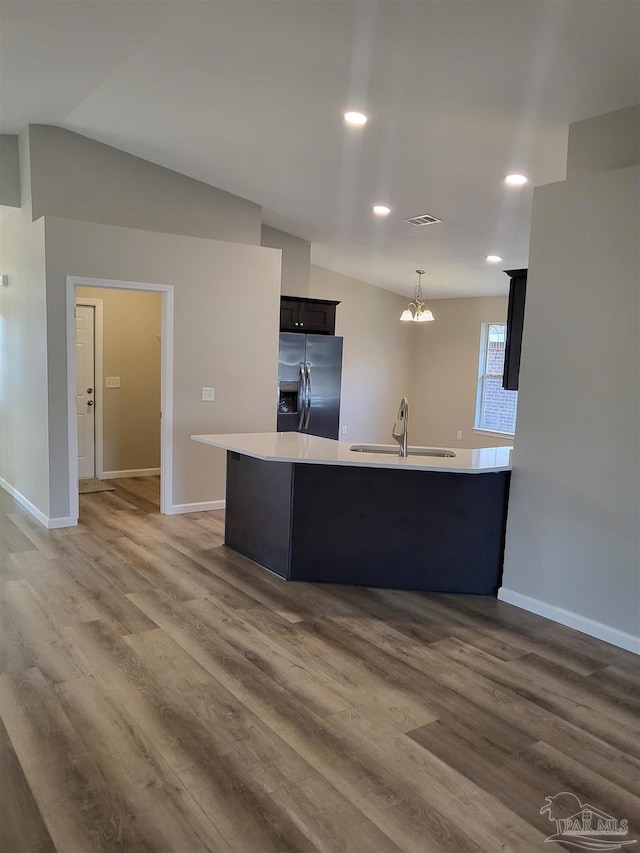 kitchen featuring kitchen peninsula, stainless steel fridge, hardwood / wood-style flooring, vaulted ceiling, and sink