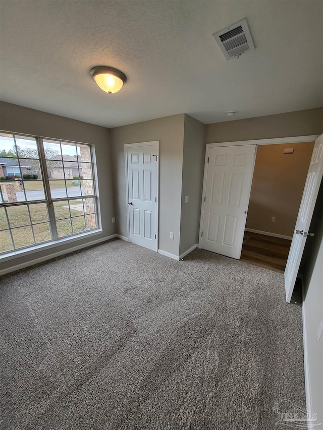 unfurnished bedroom featuring a textured ceiling and carpet