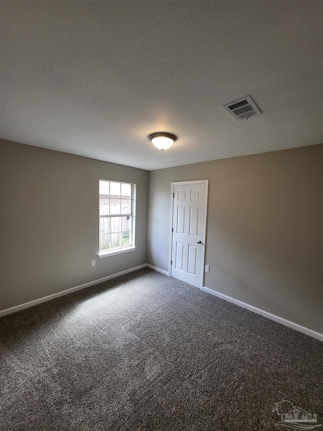 empty room with a textured ceiling and carpet flooring