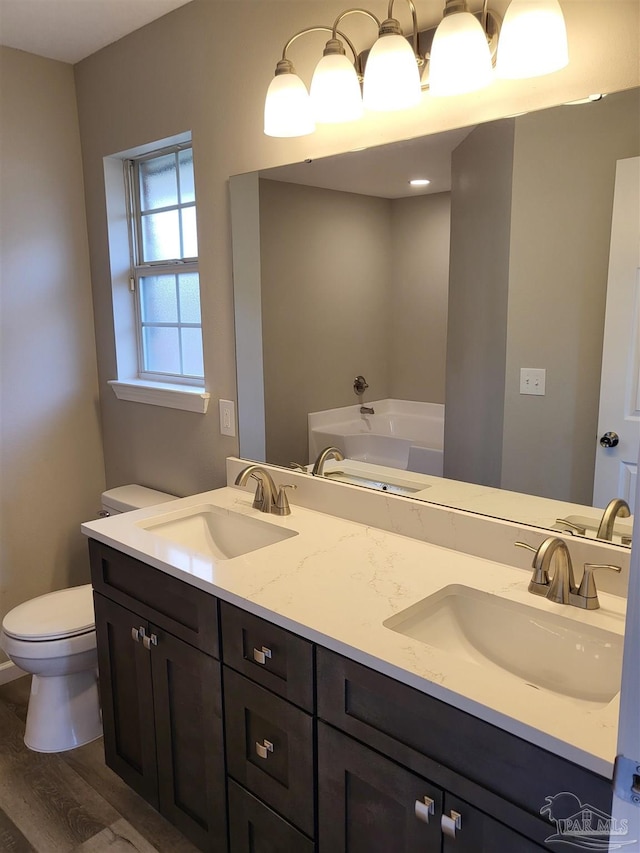 bathroom with vanity, toilet, a bathing tub, and hardwood / wood-style floors