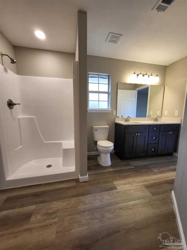 bathroom with vanity, a shower, hardwood / wood-style flooring, and toilet