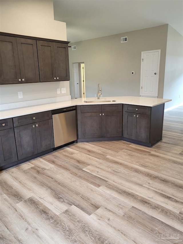 kitchen with light hardwood / wood-style flooring, kitchen peninsula, dark brown cabinets, sink, and stainless steel dishwasher