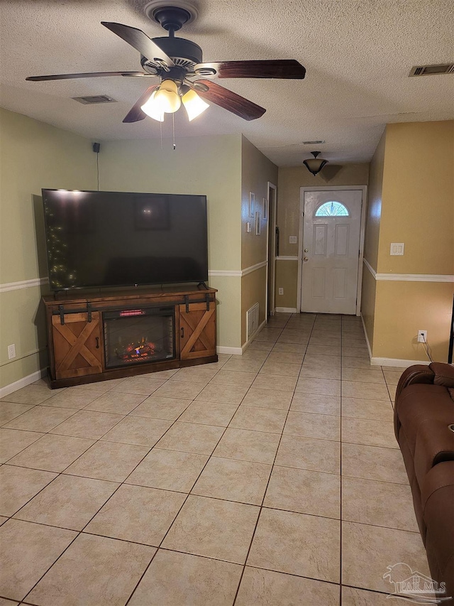 tiled living room featuring ceiling fan and a textured ceiling