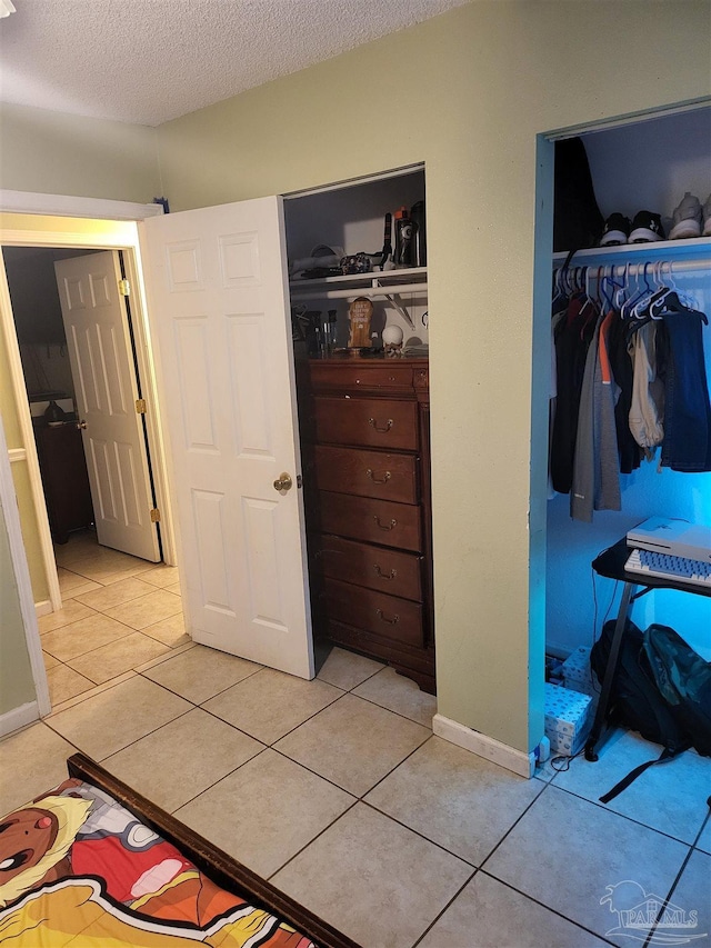 bedroom featuring multiple closets, a textured ceiling, and light tile patterned flooring