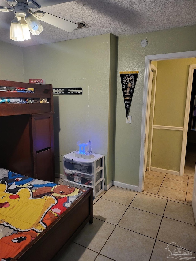 bedroom with ceiling fan, a textured ceiling, and light tile patterned floors