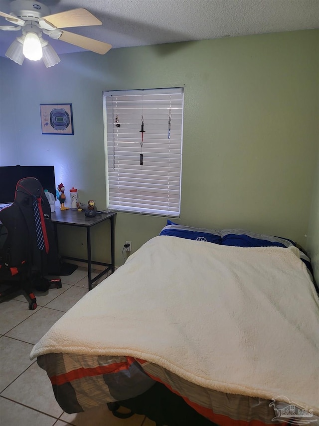 bedroom featuring light tile patterned flooring, ceiling fan, and a textured ceiling