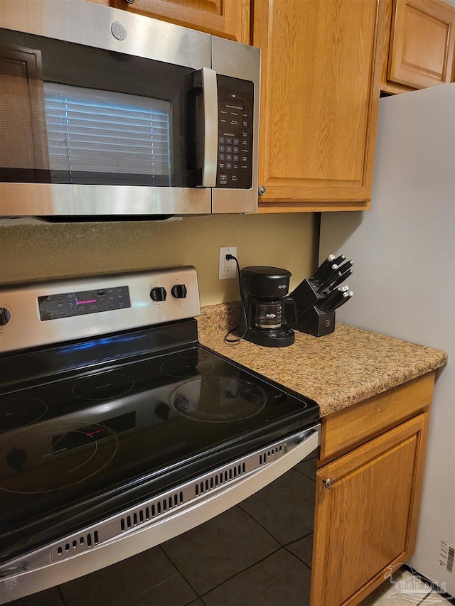 kitchen with light stone countertops, range with electric cooktop, and white fridge