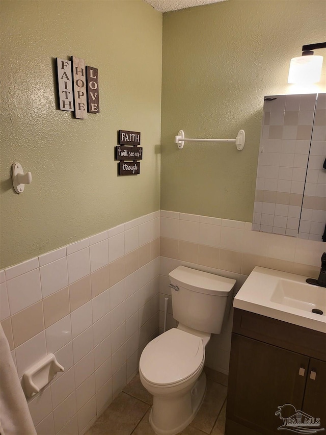 bathroom featuring vanity, tile walls, tile patterned floors, and toilet