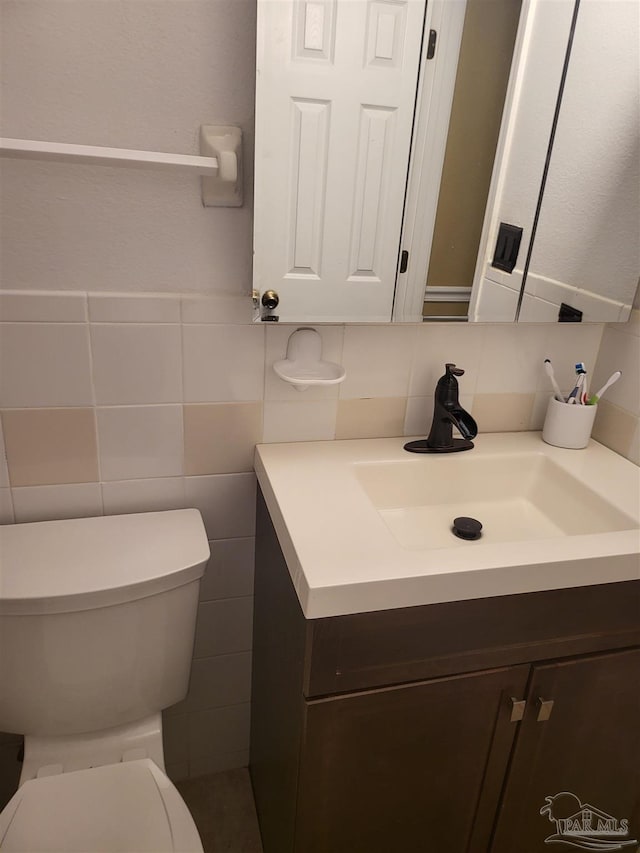 bathroom with vanity, tile walls, and toilet