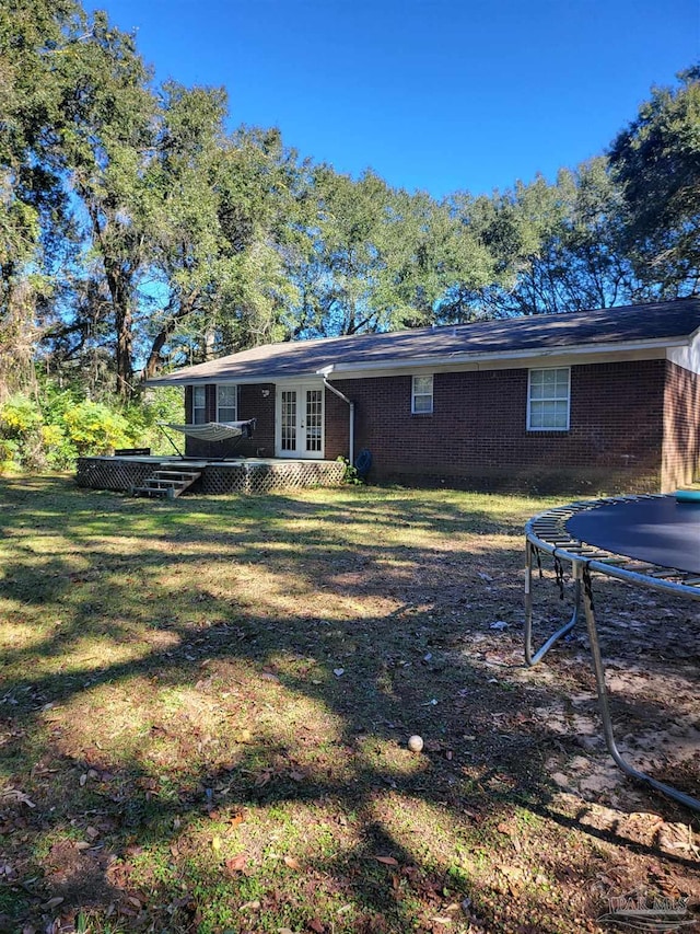 back of house featuring a trampoline and a yard