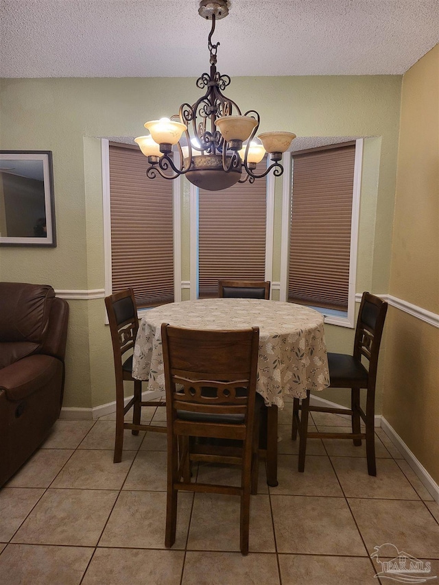 dining area with a notable chandelier, a textured ceiling, and light tile patterned floors