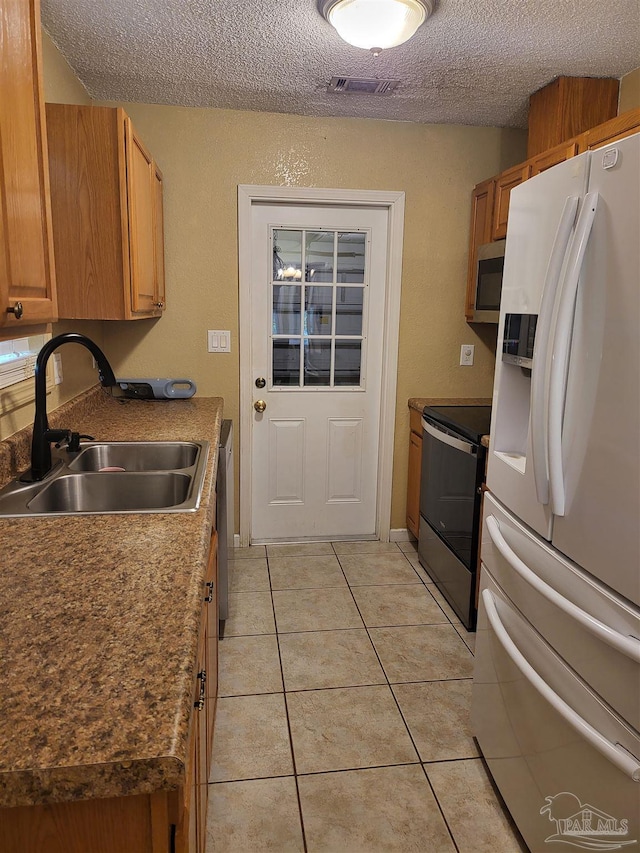 kitchen featuring light tile patterned flooring, appliances with stainless steel finishes, sink, and a textured ceiling