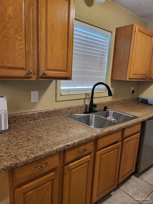 kitchen featuring dishwasher, sink, a textured ceiling, and light tile patterned floors