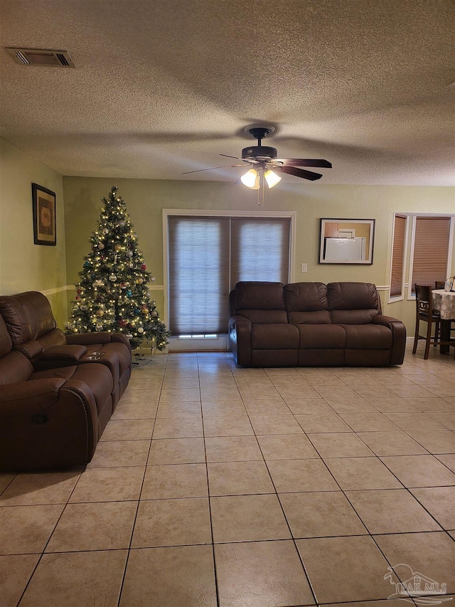 tiled living room with ceiling fan and a textured ceiling