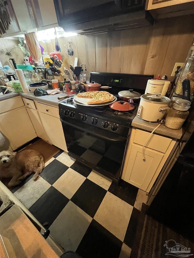 kitchen with wooden walls, electric range, tile patterned floors, and white cabinetry