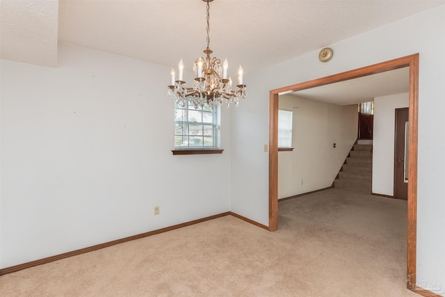 empty room with an inviting chandelier, light carpet, and a textured ceiling