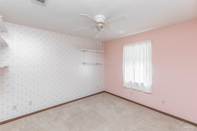 empty room featuring ceiling fan, light colored carpet, and a textured ceiling