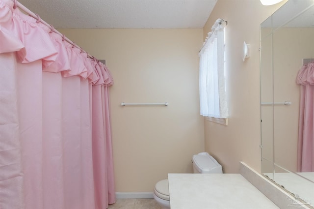 bathroom with tile patterned flooring, vanity, a textured ceiling, and toilet