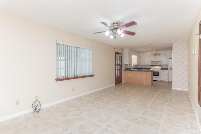 kitchen featuring tasteful backsplash, white cabinets, ceiling fan, kitchen peninsula, and white appliances